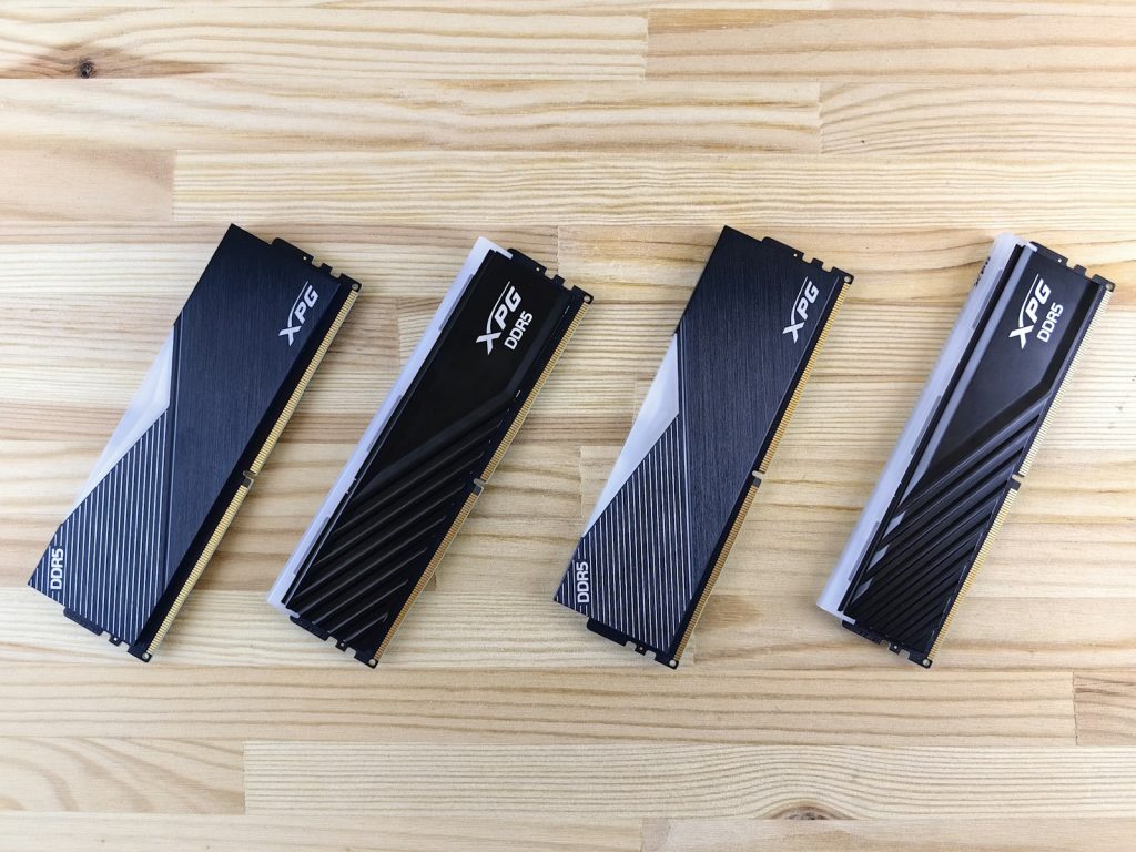 Cuatro módulos de memoria DDR5 con disipador metálico negro sobre una superficie de madera