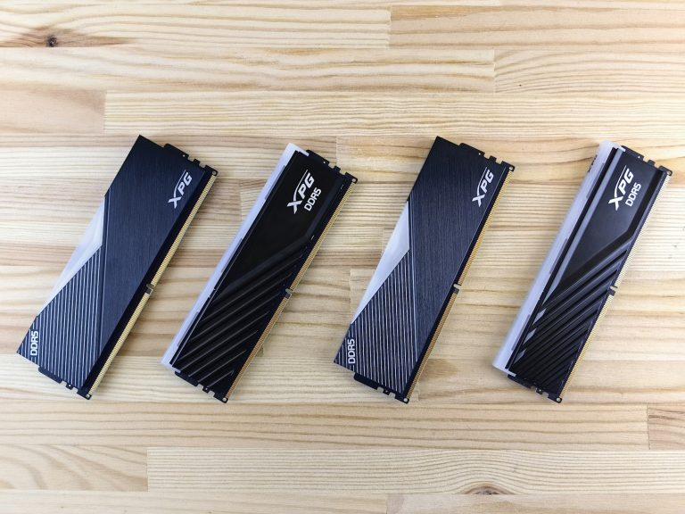 Cuatro módulos de memoria DDR5 con disipador metálico negro sobre una superficie de madera